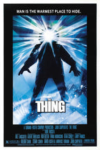 The Thing movie poster wall art print features a dark parka-clad figure with a blazing white face amid icy blue rays.
