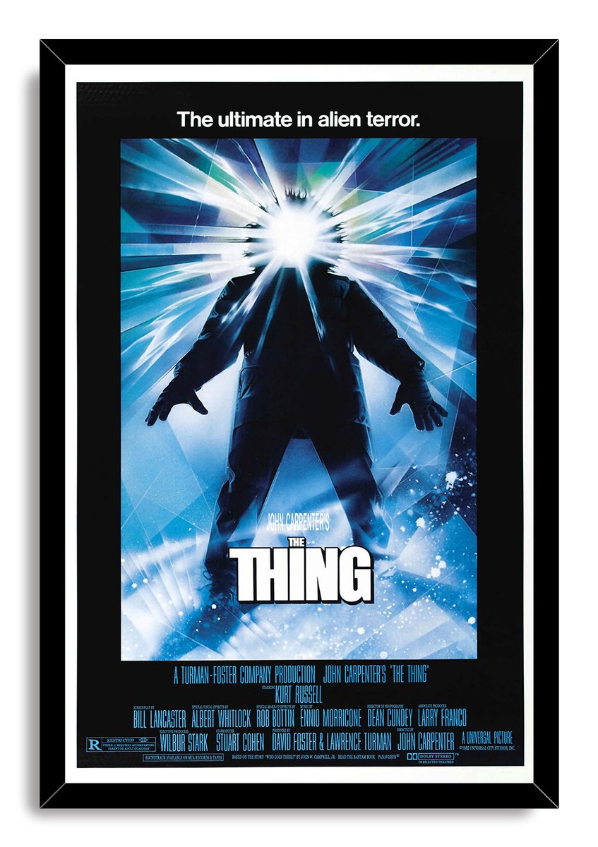 The Thing framed wall art print in a black frame, depicting a shadowed figure beneath a radiant white flare and icy blue rays.