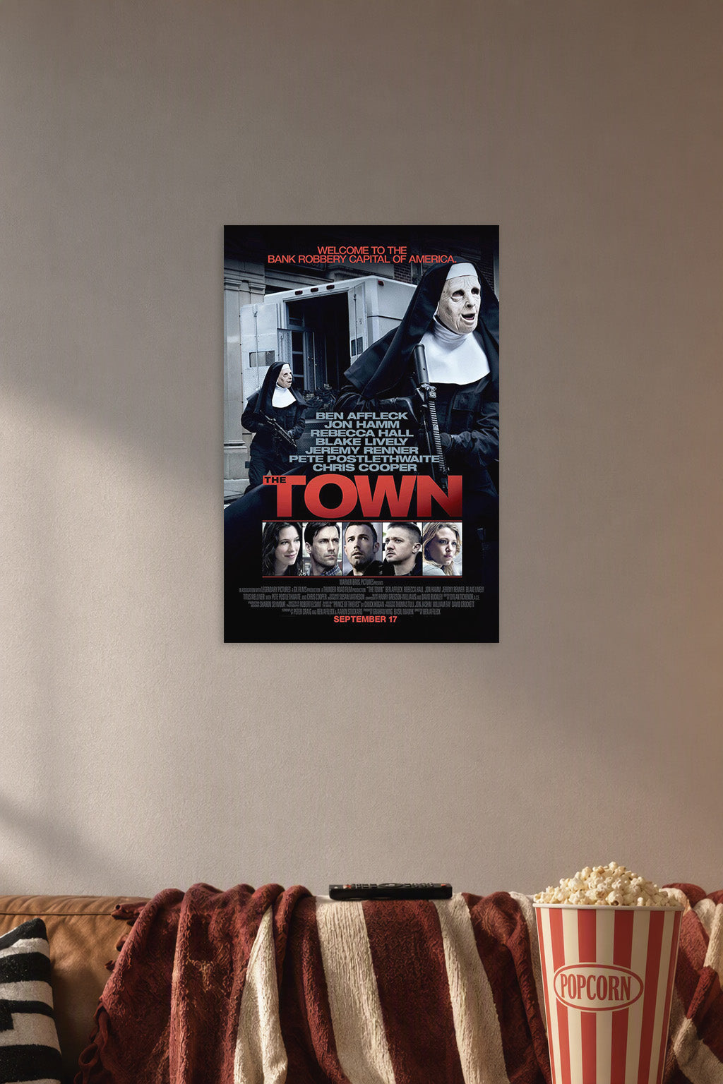 The Town Movie Poster in a cozy movie room above a brown sofa with popcorn.