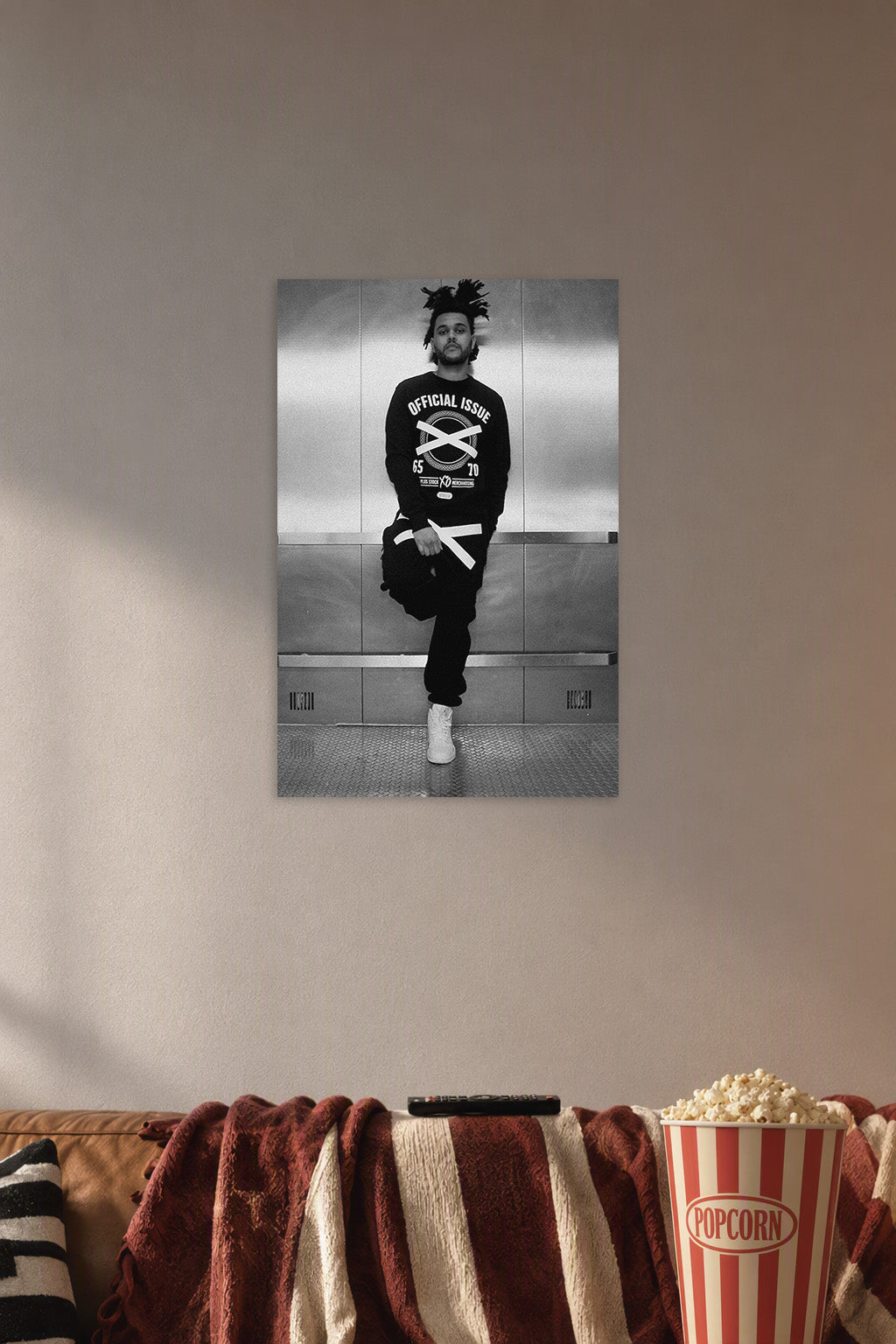 The Weeknd in a cozy movie room above a brown sofa with popcorn.