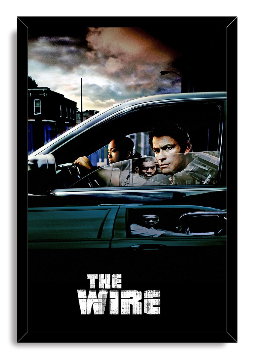 The Wire framed wall art print presents men in a dark sedan under a moody sky, bordered by a black frame with white title text.
