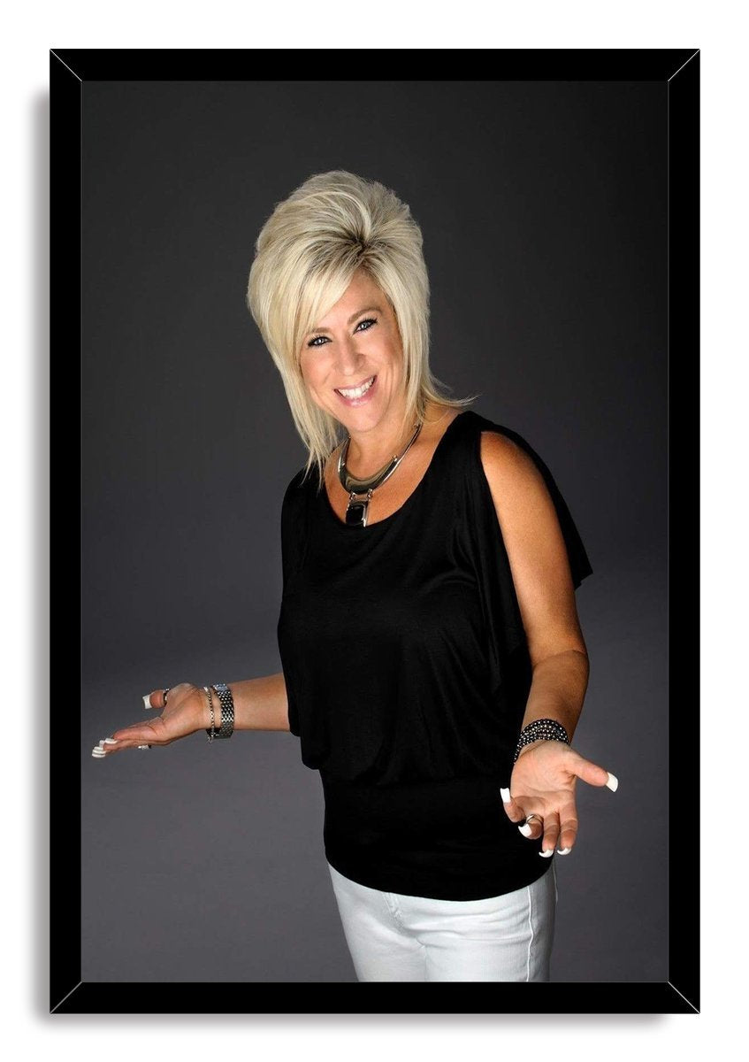 Theresa Caputo framed wall art print, a blonde woman smiling with open palms against a dark gray studio backdrop.