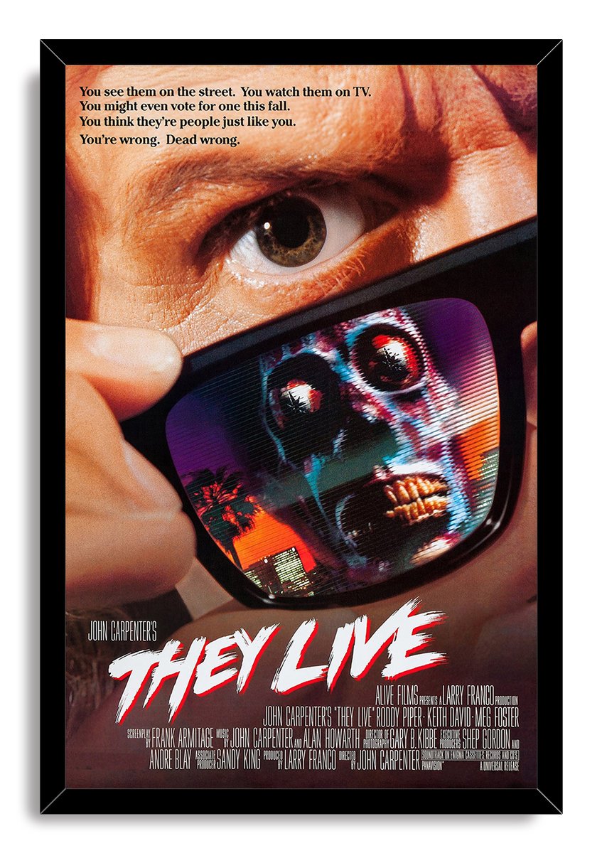 They Live framed wall art print presents a man’s eye above sunglasses reflecting a blue alien against orange city lights.