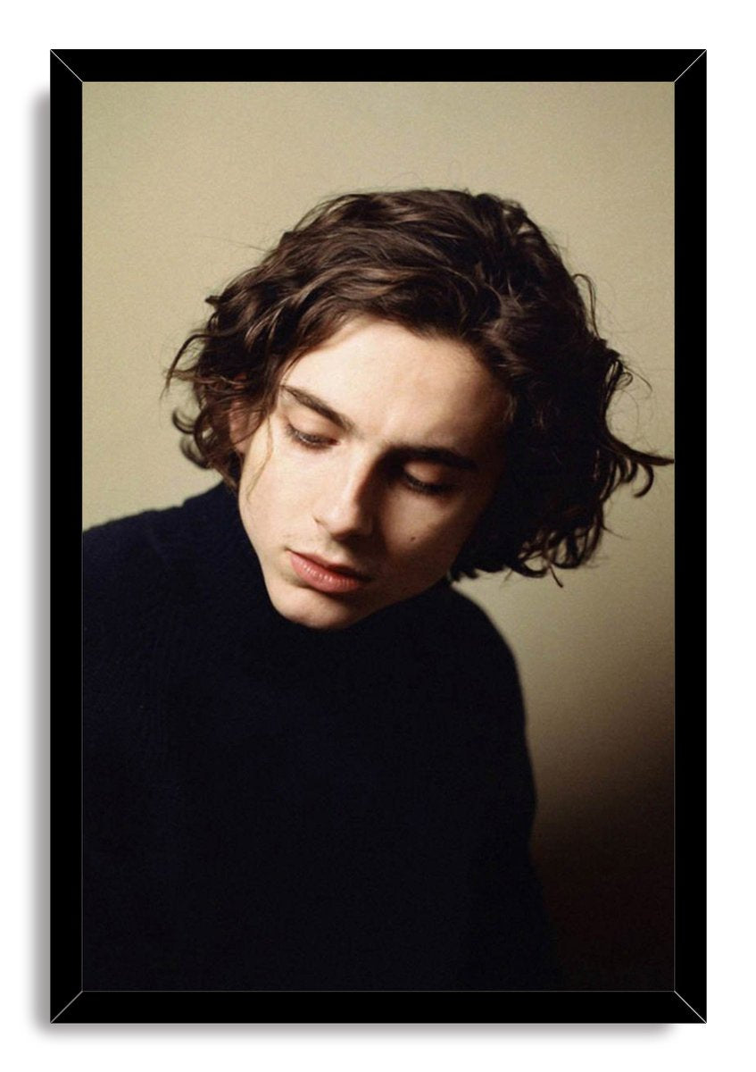 Timothée Chalamet framed wall art print with a black border, featuring his curled dark hair, lowered eyes, and dark sweater.