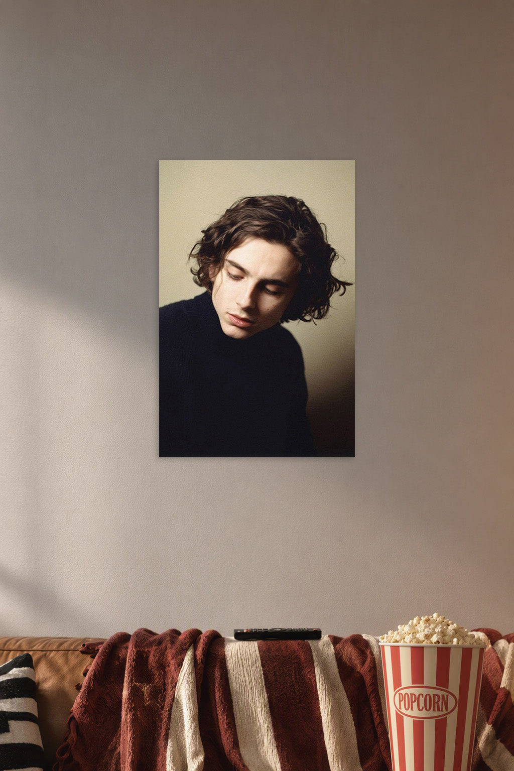 Timothée Chalamet in a cozy movie room above a brown sofa with popcorn.