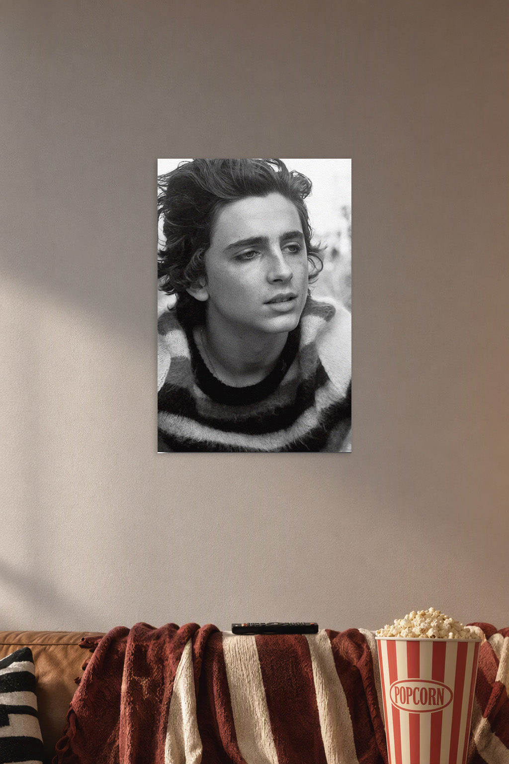 Timothée Chalamet in a cozy movie room above a brown sofa with popcorn.
