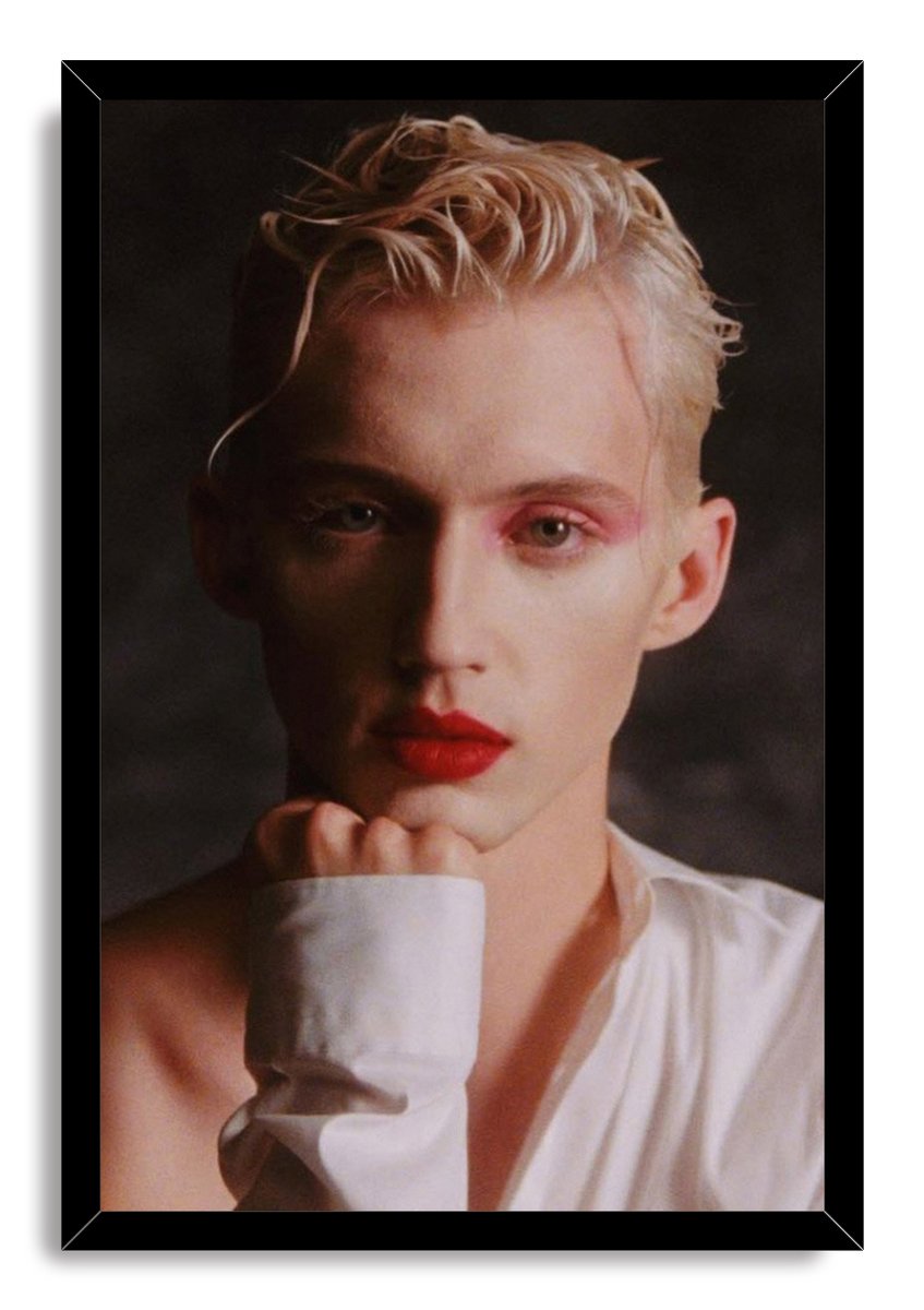 Troye Sivan framed wall art print in a black frame, portraying him with pink eye shadow, red lipstick and tousled blond hair.