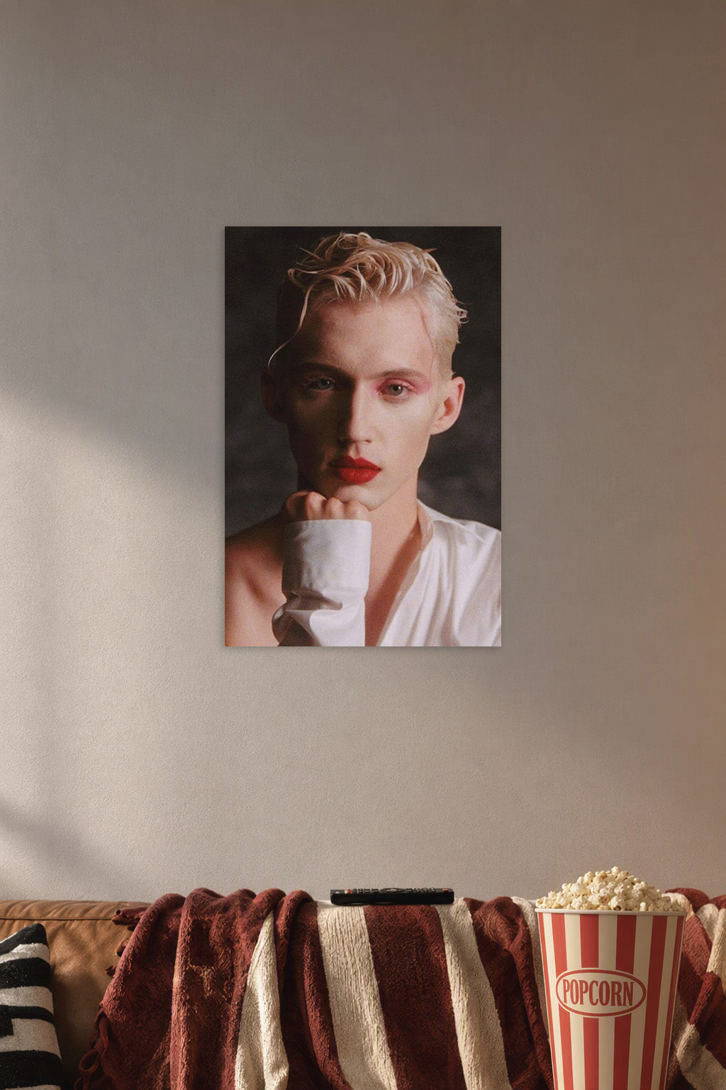 Troye Sivan in a cozy movie room above a brown sofa with popcorn.