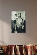 Tupac Shakur in a cozy movie room above a brown sofa with popcorn.