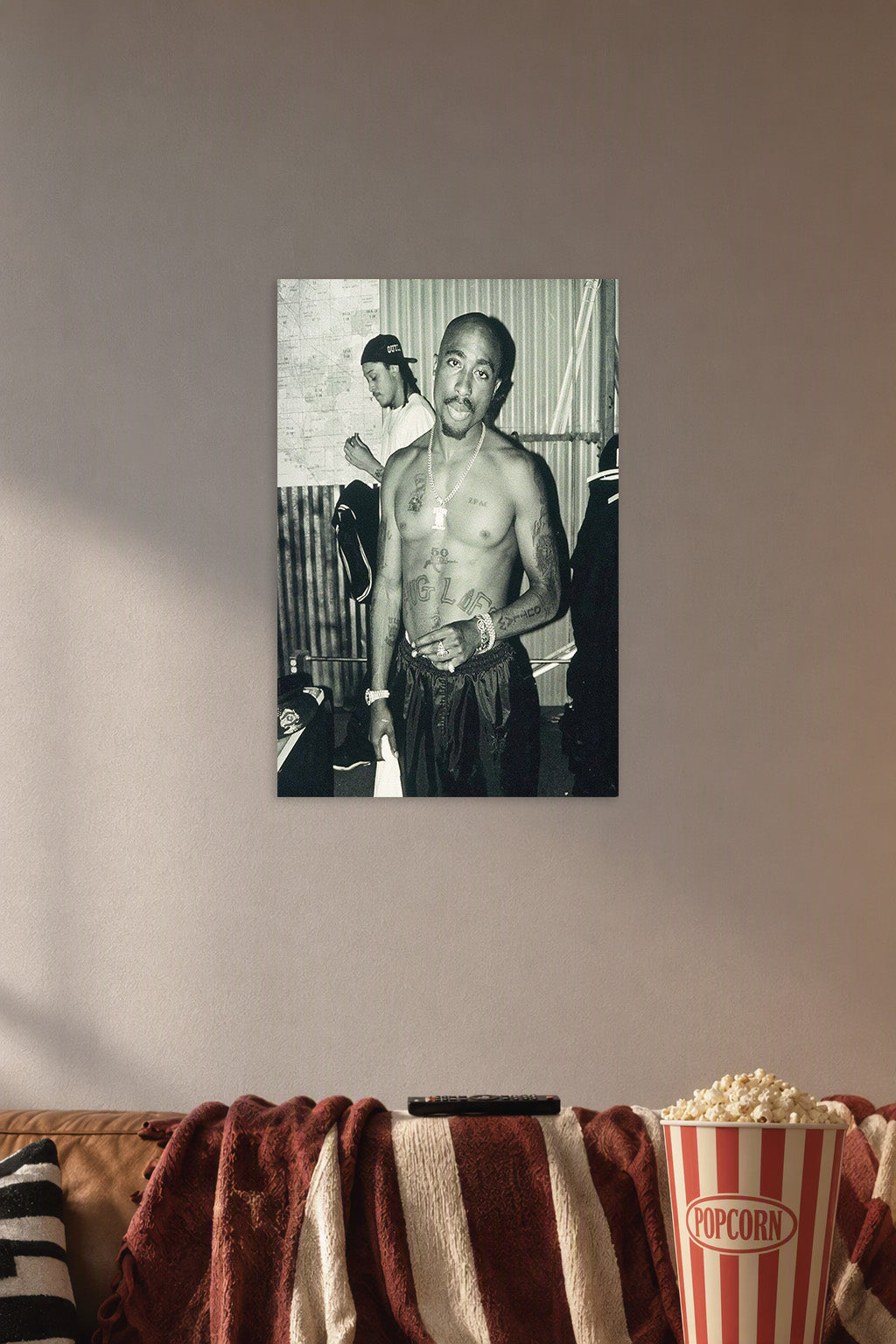 Tupac Shakur in a cozy movie room above a brown sofa with popcorn.