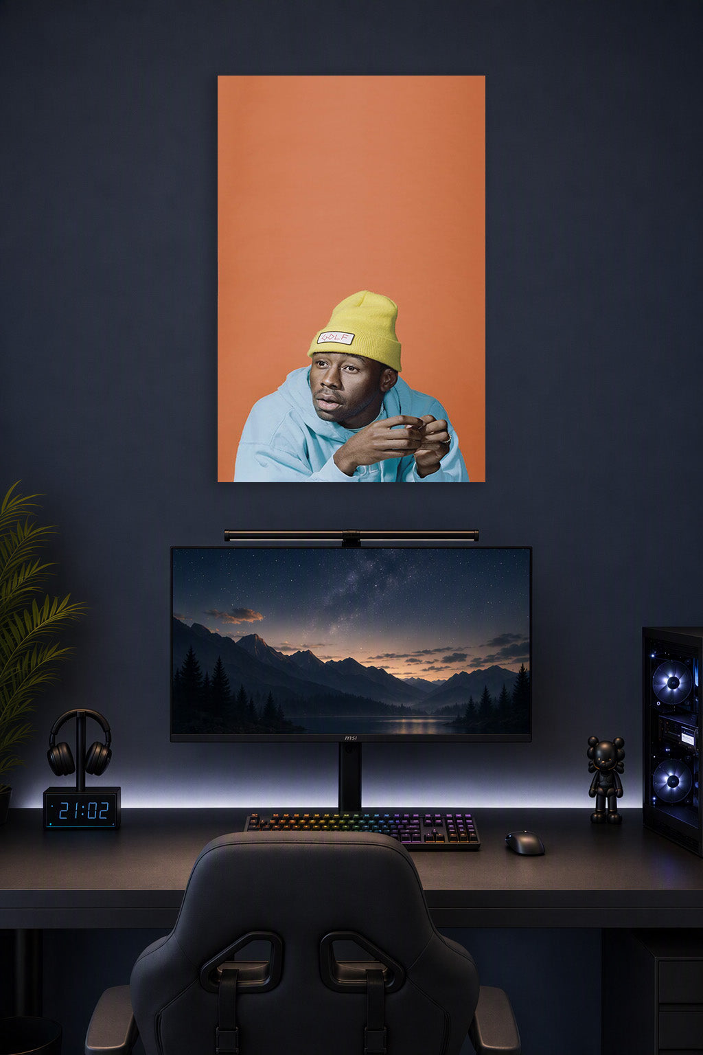 Tyler, The Creator in a gaming desk setup above a monitor.