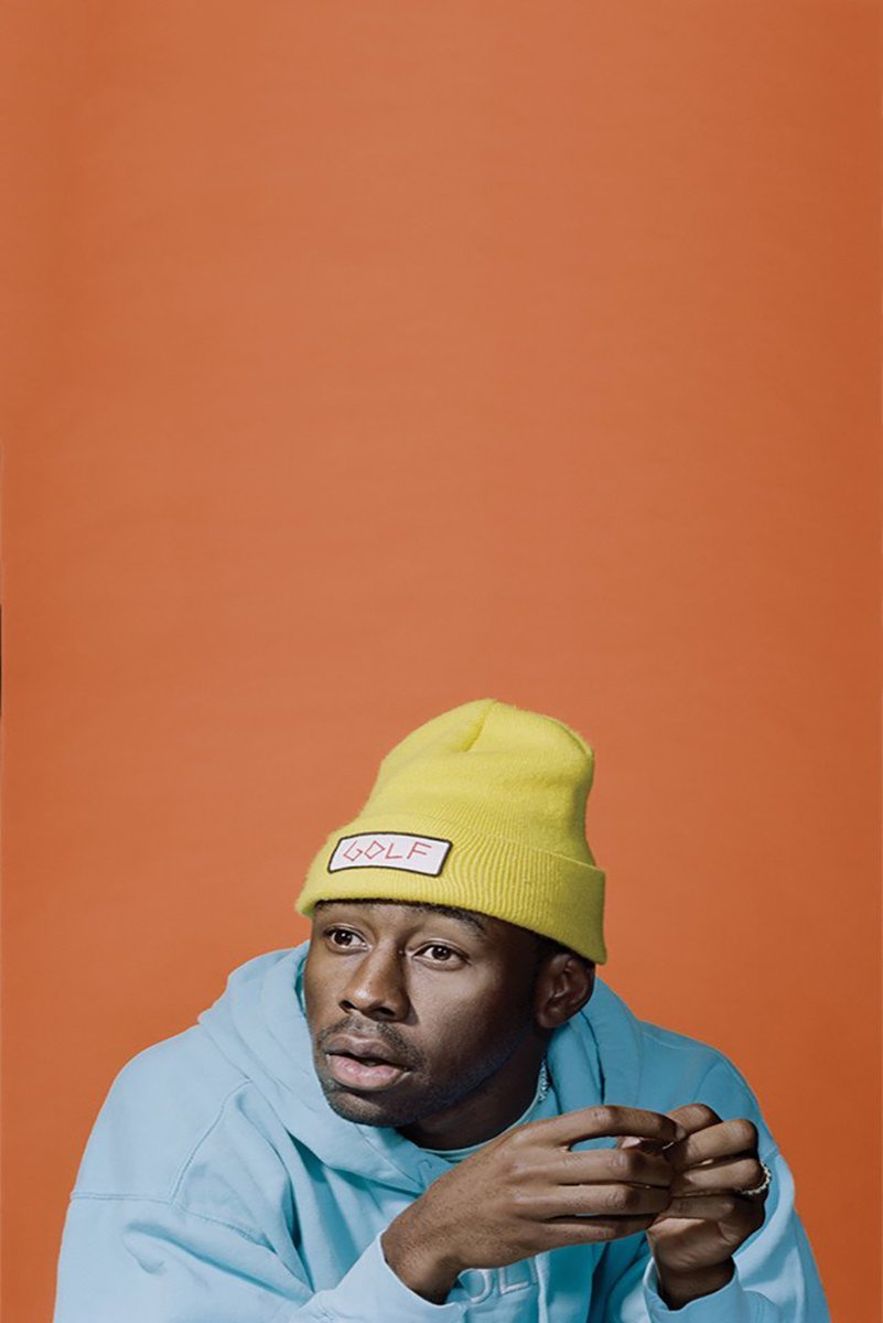 Tyler, The Creator wall art print features a close portrait in a yellow GOLF beanie and blue hoodie against orange.