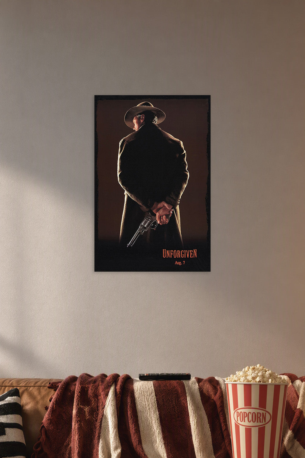 Unforgiven Movie Poster in a cozy movie room above a brown sofa with popcorn.
