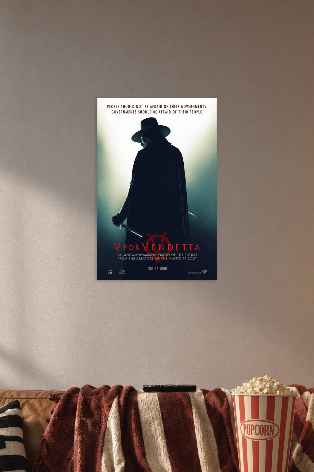 V for Vendetta in a cozy movie room above a brown sofa with popcorn.