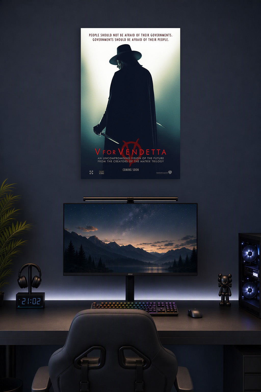 V for Vendetta in a gaming desk setup above a monitor.