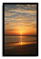 Framed sunset beach wall art print with a black border, golden sunlit water, textured sand, and layered evening clouds.