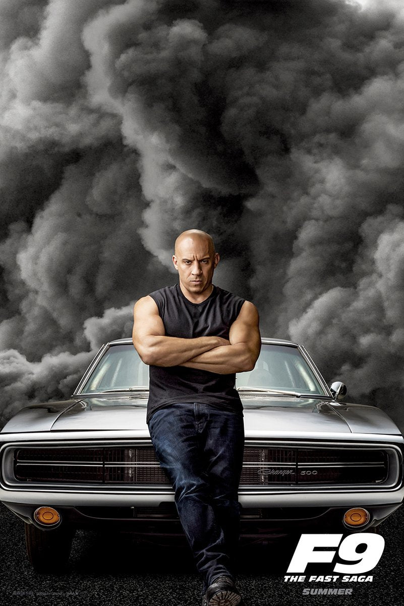Vin Diesel F9 The Fast Saga poster with Dominic Toretto standing arms crossed before a silver muscle car and storm clouds.