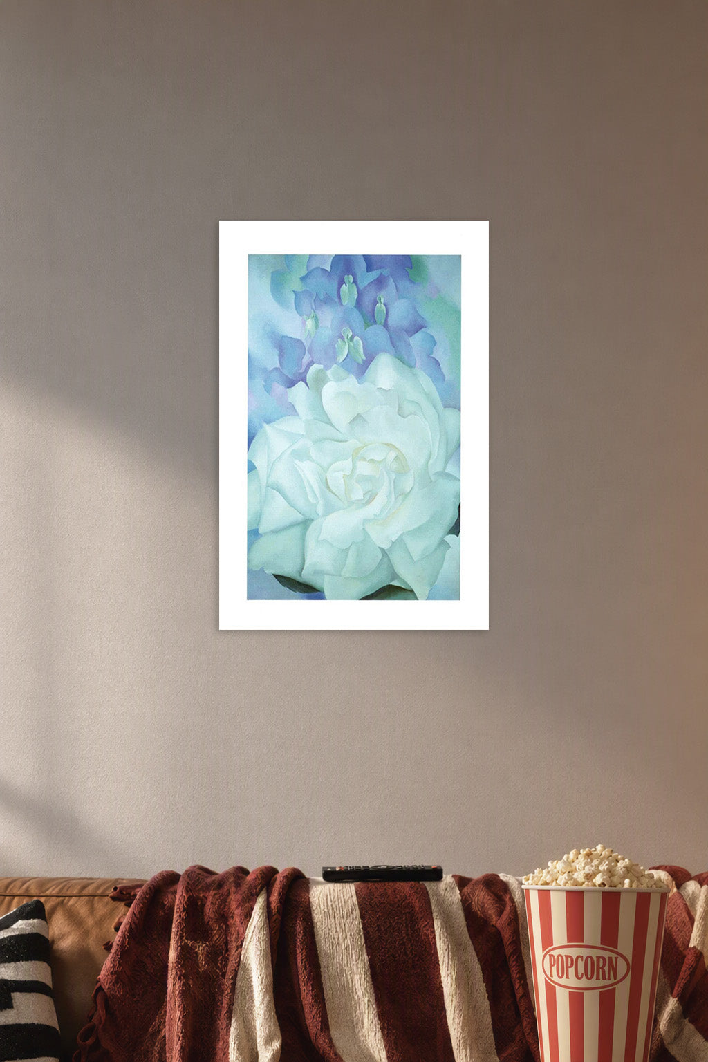 White Floral Art in a cozy movie room above a brown sofa with popcorn.
