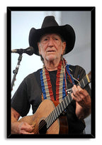 Willie Nelson framed wall art print portrays the musician playing an acoustic guitar beside a microphone, set in a black frame.