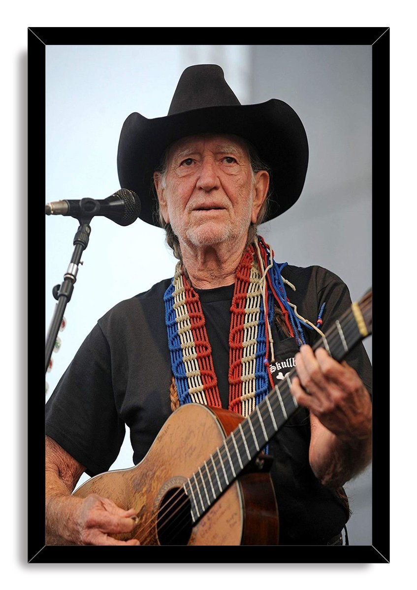 Willie Nelson framed wall art print portrays the musician playing an acoustic guitar beside a microphone, set in a black frame.