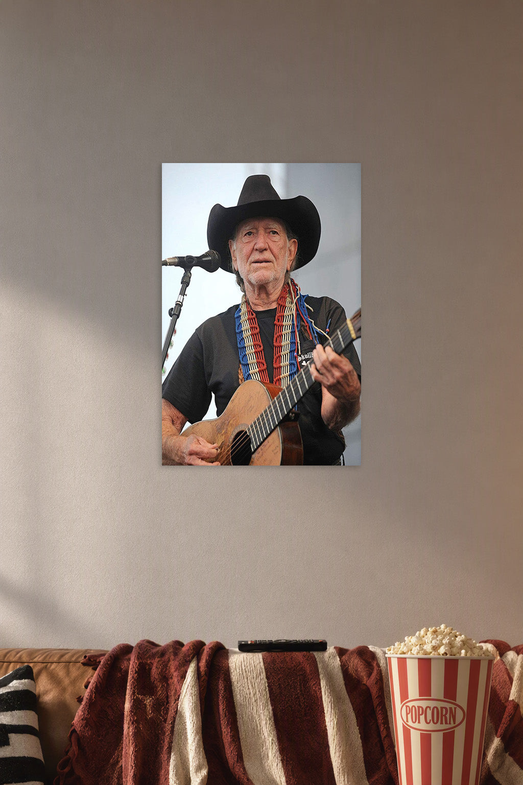 Willie Nelson in a cozy movie room above a brown sofa with popcorn.