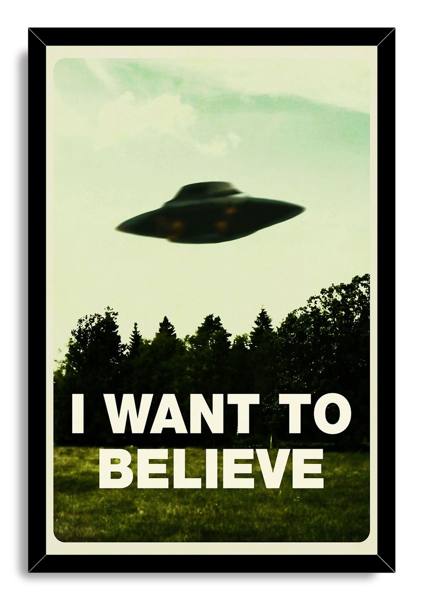 I Want To Believe framed wall art print with a black border, a shadowy UFO over a tree line, and bold white lettering.