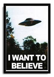 UFO wall art print framed in black, depicting a saucer in a pale sky above trees and bold "I WANT TO BELIEVE" text.