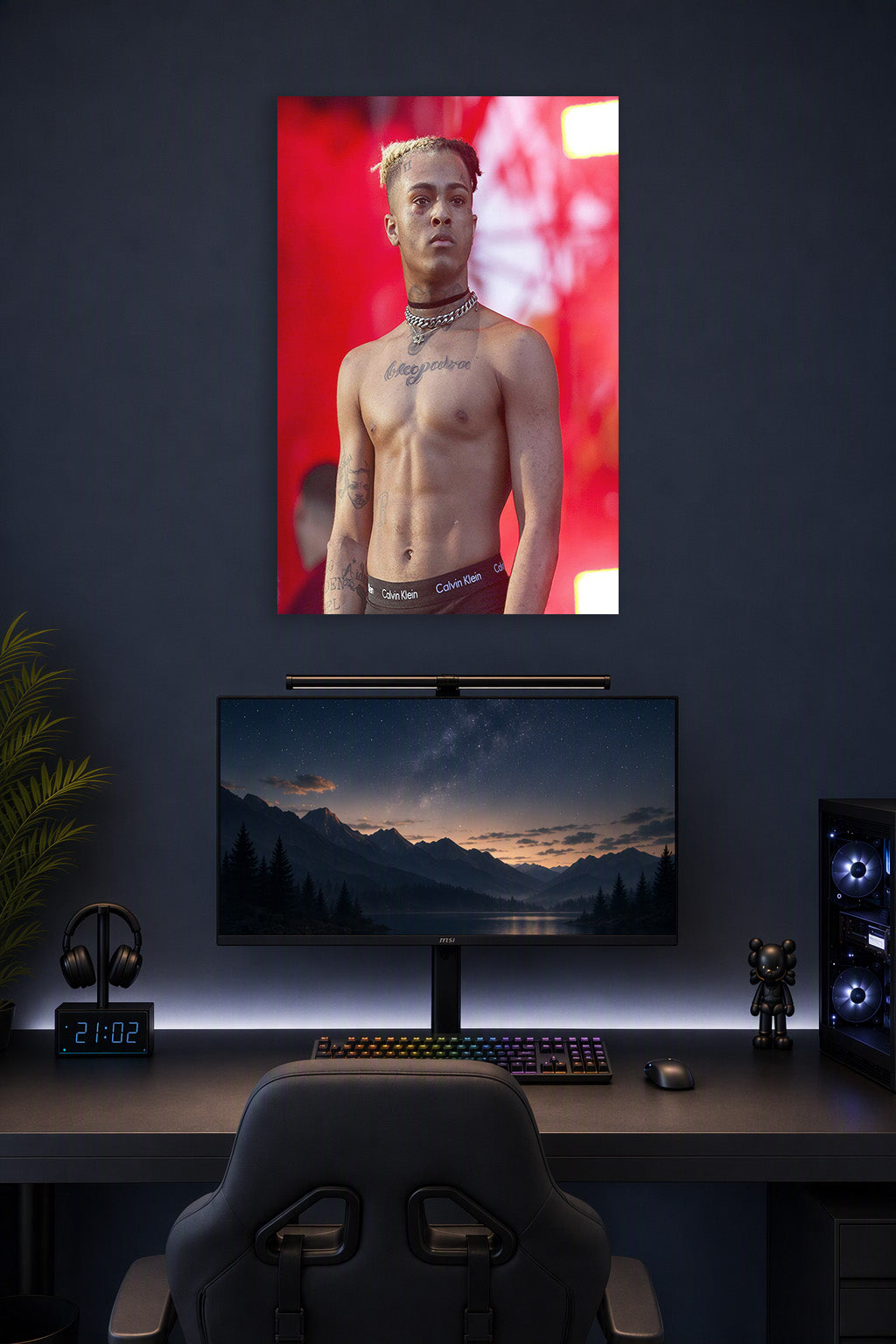 XXXTentacion in a gaming desk setup above a monitor.