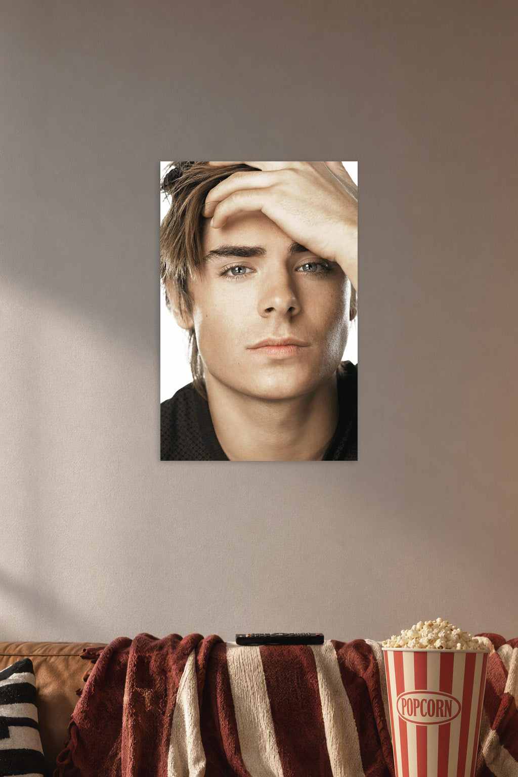 Zac Efron in a cozy movie room above a brown sofa with popcorn.