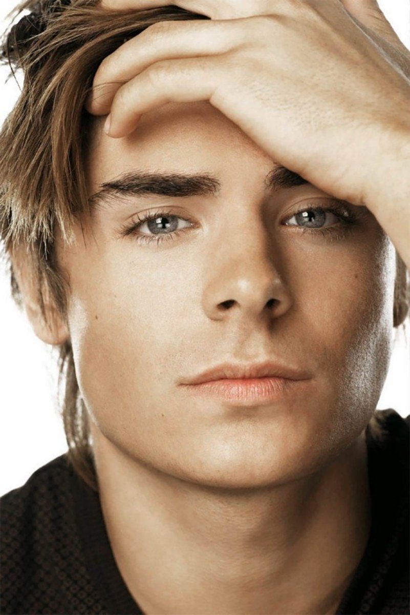 Zac Efron poster close-up portrait with tousled brown hair, gray eyes, and one hand resting across his forehead.