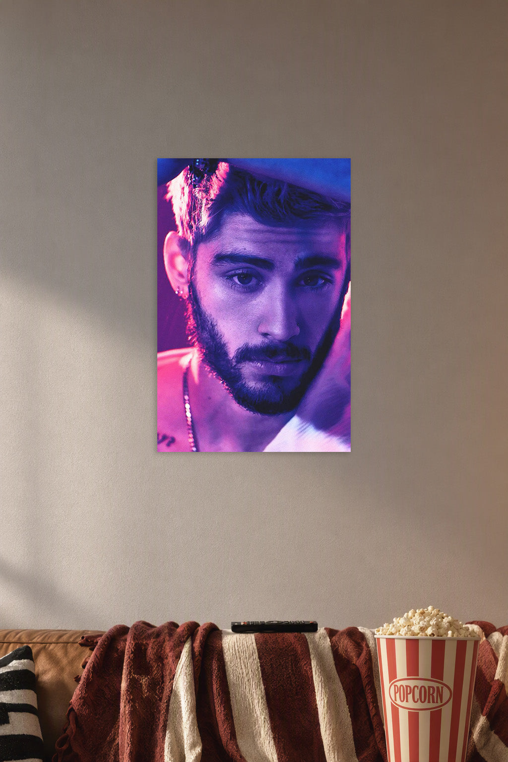 Zayn Malik in a cozy movie room above a brown sofa with popcorn.