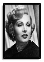 Zsa Zsa Gabor framed wall art print displays a monochrome portrait of the actress in a black frame, wearing pearls and jeweled earrings.