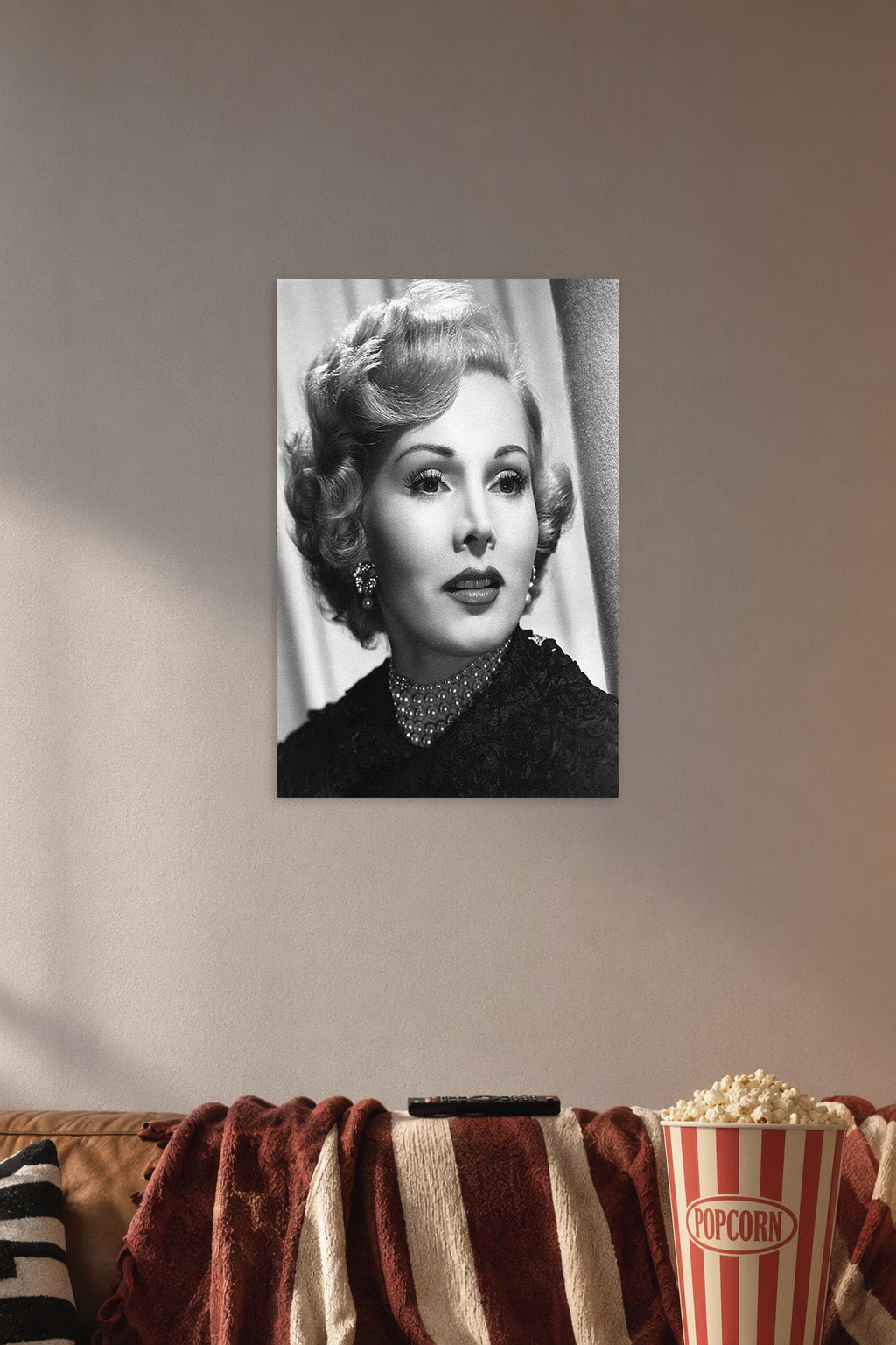Zsa Zsa Gabor in a cozy movie room above a brown sofa with popcorn.